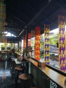 a restaurant with a bar with tables and stools at Ma Guesthouse Chiang Mai in Chiang Mai