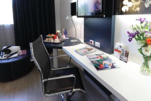 a desk with a chair and a table with flowers at Holiday Inn Milan Nord Zara, an IHG Hotel in Cinisello Balsamo