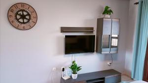 a room with a clock and a tv on a wall at Grace resident stúdió apartman in La Mata