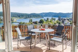 un tavolo e sedie su un balcone con vista sul lago di Ferienwohnung Seeglück mit großzügigem Südbalkon und herrlichem Seeblick a Schluchsee