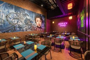 a restaurant with tables and chairs and a large mural at Ashley Tang Menteng Jakarta in Jakarta