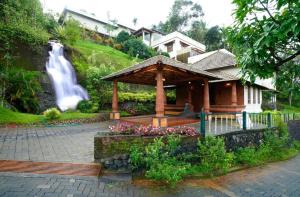 a house with a gazebo next to a waterfall at Indeevara Retreat, Wayanad in Vythiri