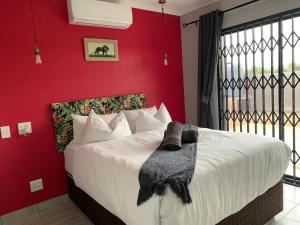 - une chambre avec un grand lit et un mur rouge dans l'établissement Lion House, 3 bedroom House next to Pilanesberg and Sun City, à Mogwase