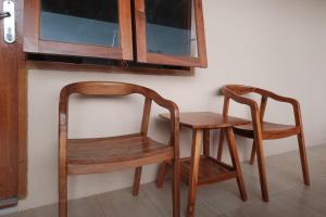 2 sillas de madera, mesa de madera, mesa y silla en RedDoorz Plus Syariah at Hotel Indonesia Kajen en Pekalongan