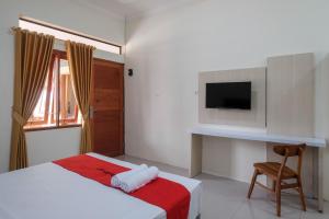a bedroom with a bed and a tv and a chair at RedDoorz Plus Syariah at Hotel Indonesia Kajen in Pekalongan