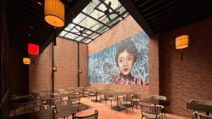 a room with tables and chairs and a large painting on the wall at Ashley Tang Menteng Jakarta in Jakarta