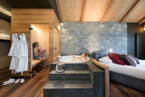 un dormitorio con bañera y cama y un hombre en un espejo en Hotel Lac Salin Spa & Mountain Resort, en Livigno