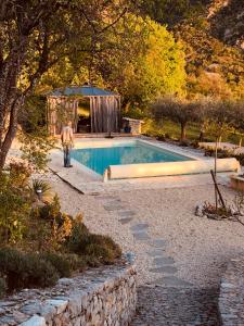 un hombre caminando junto a una piscina en FONT NOUVELLE maison de charme Drôme Provençale, 6 ou 10 personnes avec piscine, en Plaisians