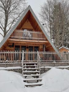 une cabane en rondins dans la neige avec une clôture blanche dans l'établissement Wildkräuter Hexenhaus, à Mauth