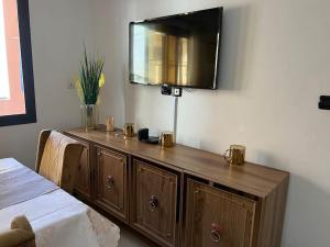 a wooden cabinet with a television on a wall at TérangaLux Appartement Le Yoruba Dakar Sacré Cœur 3 in Dakar