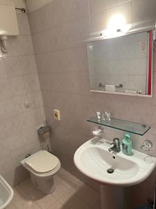 a bathroom with a sink and a toilet and a mirror at Hotel Mazzini in Lido di Jesolo