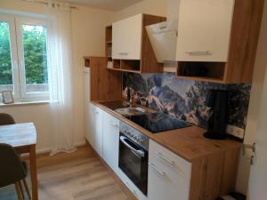 a kitchen with white cabinets and a sink and a stove at Ferienwohnung Maustadt in Memmingen +12 photos