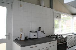 a kitchen with white tile walls and a counter top at Rekerlanden 90 in Schoorldam