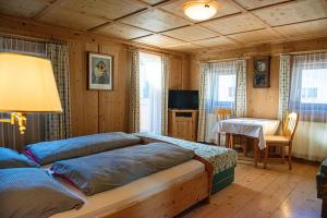 Schlafzimmer mit einem Bett, einem Tisch und einem TV in der Unterkunft Rodahof in Sexten