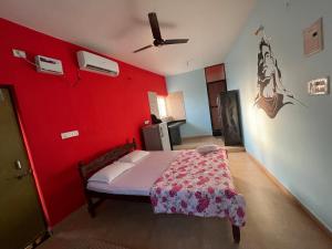 um quarto com uma parede vermelha e uma cama. em Morjim Guest House em Morjim