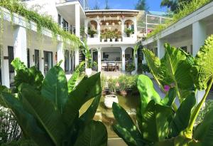 una grande casa bianca con piante in primo piano di Coto Island Beach Village Homestay a Đảo Cô Tô