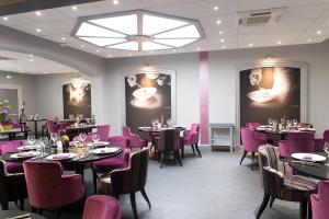 une salle à manger avec des tables et des chaises violettes dans l'établissement Logis Hôtel de France restaurant le Lucullus, à Montmorillon