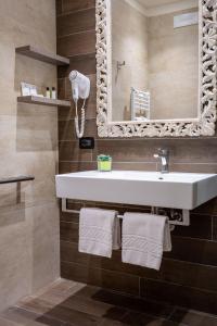 a bathroom with a sink and a mirror and towels at Litoraneo Suite Hotel in Rimini