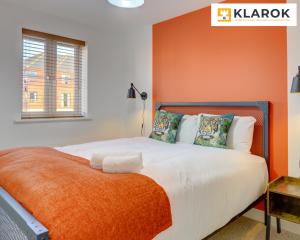 a bedroom with a bed with an orange accent wall at LARGE 4 Bedroom Semi-Detached House Sleeps 7 By Klarok Short Lets & Serviced Accommodation in Peterborough