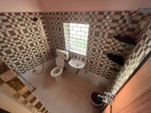 uma casa de banho com um WC e uma janela em Morjim Guest House em Morjim