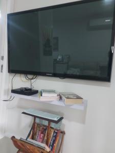 a flat screen tv hanging on a wall with books at Cascabelbnb Private 2BR apartment in Noarlunga