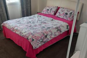 Cama con edredón y almohadas de color rosa y blanco en Cascabelbnb Private 2BR apartment, en Noarlunga