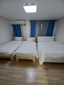 two beds in a room with blue curtains at J&J Guesthouse in Jeonju