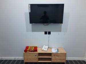 جوهرة القنفذة في القنفذة: تلفزيون بشاشة مسطحة على جدار أبيض مع طاولة خشبية