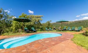 a swimming pool with chairs and an umbrella at Iketla Lodge in Ohrigstad