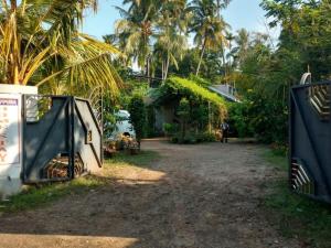 阿勒皮的住宿－Kalappura Homestay，通往带房子和棕榈树的院子的大门