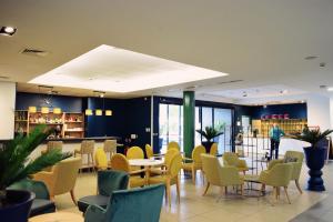 a restaurant with yellow chairs and tables in a building at Domitys - L'HERMINE BLANCHE in Wasquehal +2 photos