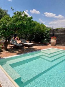 una piscina en un patio con una mesa y un banco en La zagara e l'arancio, en Caltanissetta