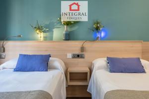 two beds with blue pillows in a room at Palamós Exclusive Apartments in Palamós