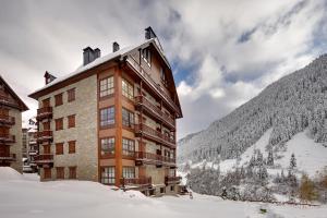 un grand bâtiment dans la neige avec une montagne dans l'établissement Val de Ruda Luxe 16 by FeelFree Rentals, à Baqueira-Beret