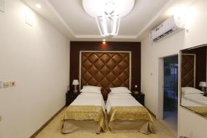 a bedroom with two beds and a large headboard at فندق حصن الأبلق - Alablaq Hotel in Taymāʼ