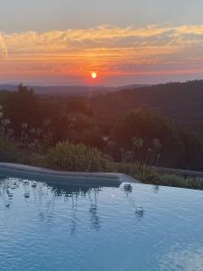 a swimming pool with the sunset in the background at Villa des Sapins in Peymeinade