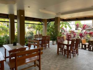 un restaurante con mesas de madera, sillas y plantas en Laph Kham House en Chiang Mai