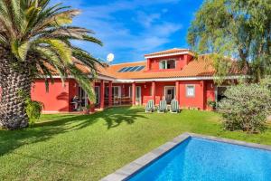 czerwony dom z palmą i basenem w obiekcie Villa Artigar, garden, swimming pool and bbq. w Puerto de la Cruz