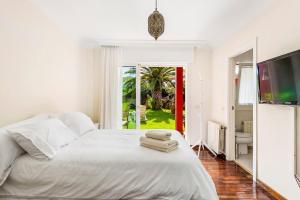 sypialnia z białym łóżkiem i ręcznikami w obiekcie Villa Artigar, garden, swimming pool and bbq. w Puerto de la Cruz