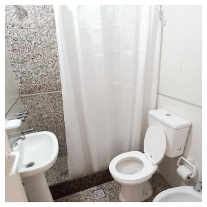 Baño blanco con aseo y lavamanos en Hotel Are Pora en Gualeguaychú