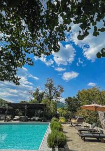 a swimming pool with chairs and an umbrella at Bourazani Wild Life Resort in Konitsa