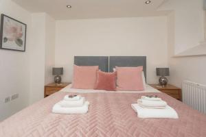 a bedroom with a pink bed with two towels on it at Panda Sanctuaries, Kensington Chapel Apartment in Bath
