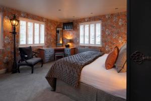 a bedroom with a bed and a desk and windows at Talland Bay Hotel, Looe in Talland