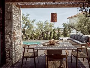 a patio with a table and chairs and a pool at Zayn Luxury Villas, a Serene Escape, By ThinkVilla in Zakynthos Town +76 photos