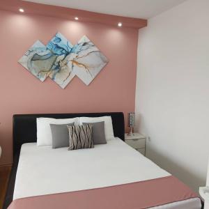 una camera da letto con un letto bianco e due dipinti alle pareti di Apartman Maja a Sombor
