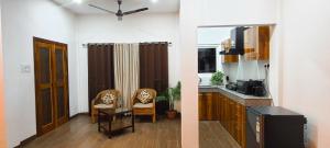 a kitchen and a living room with two chairs at Gruham Homestay in Jorhāt