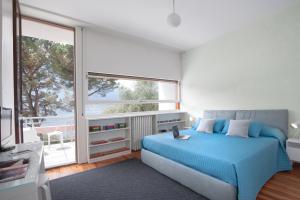 1 dormitorio con cama azul y ventana grande en Villa Glamour - Homelike Villas, en Ossuccio