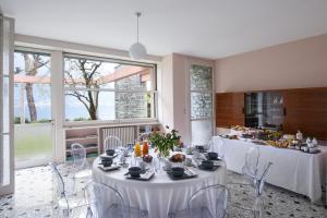 un comedor con mesas y sillas blancas y ventanas en Villa Glamour - Homelike Villas, en Ossuccio