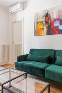 a green couch in a living room with a painting at La Dolce Vita - Luxury Stylish Flat in Trastevere 60sqm in Rome