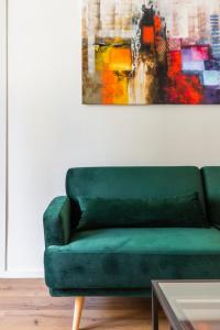 a green couch in a living room with a painting at La Dolce Vita - Luxury Stylish Flat in Trastevere 60sqm in Rome